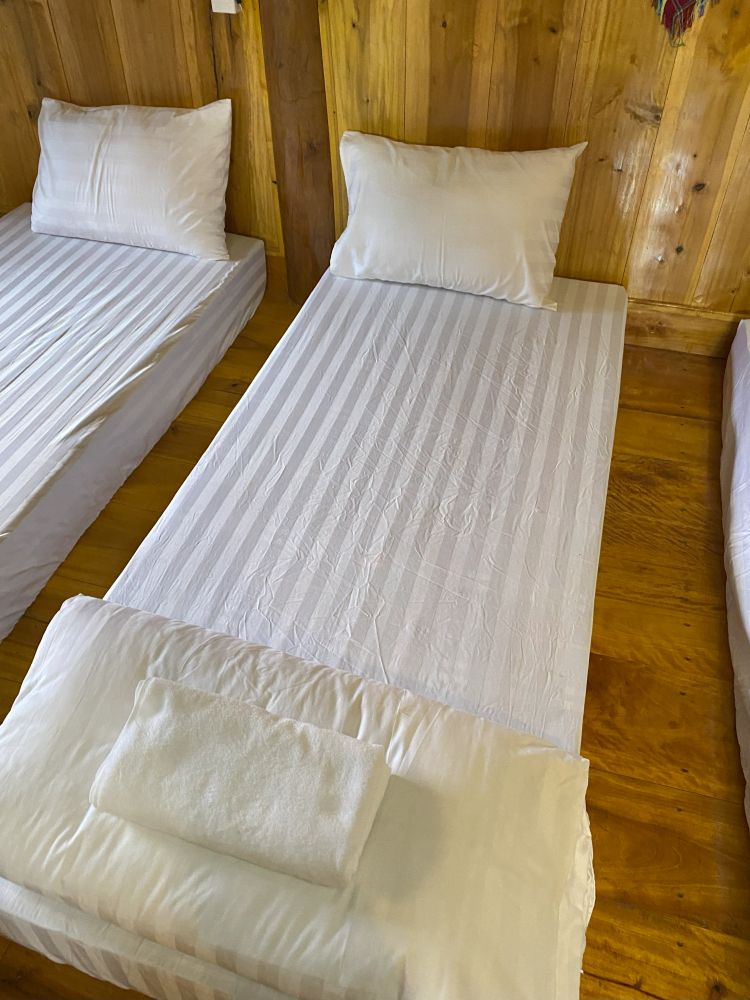 Photo of a set of mattresses with striped sheets on a wooden floor.