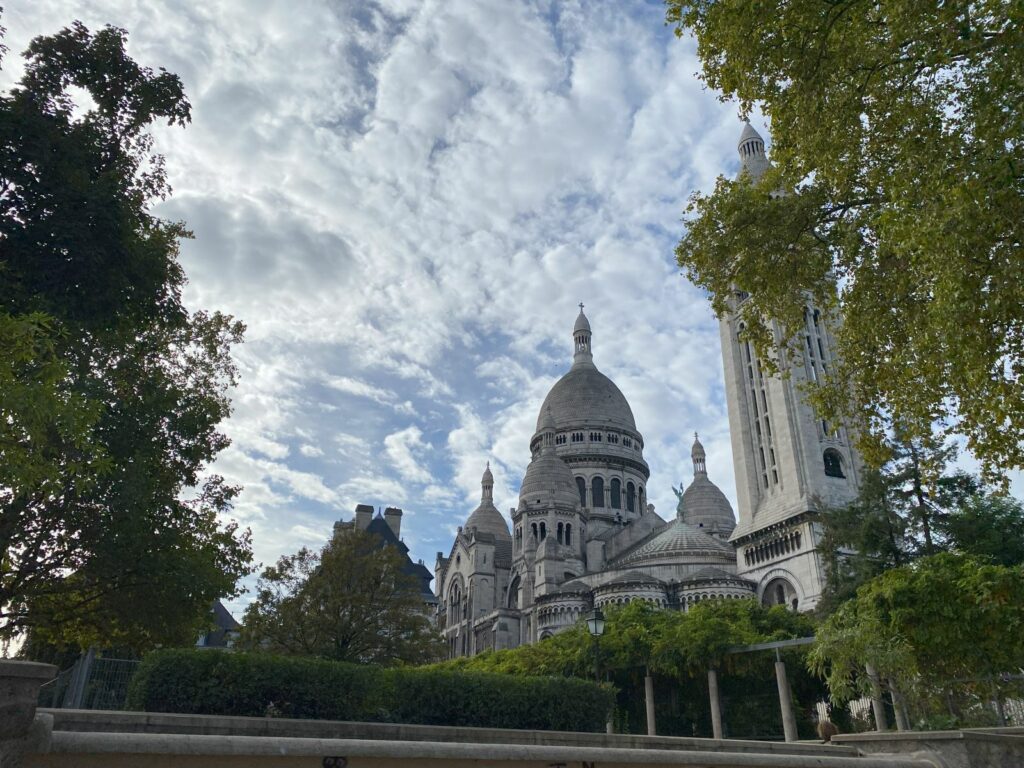 The striking white domes of Sacré-Cœur Basilica, viewed from a distance.