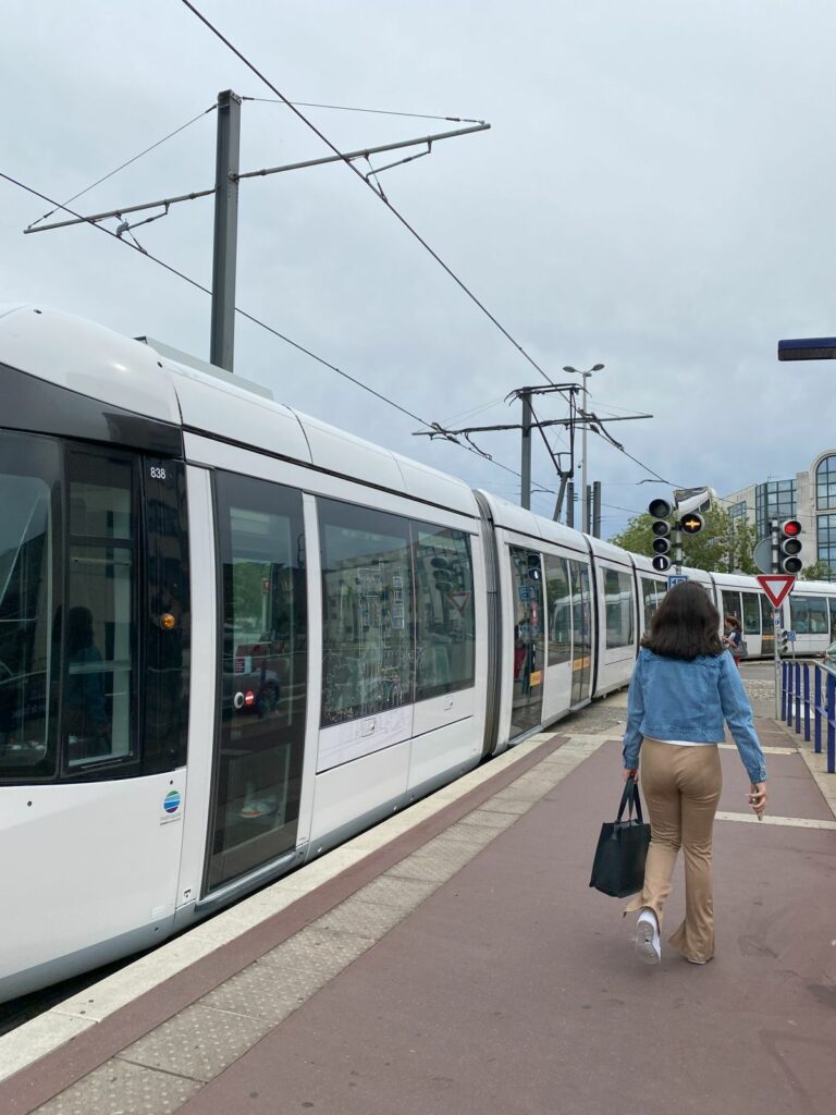 A tramway in Rouen, France, moving along the tracks with buildings in the background.