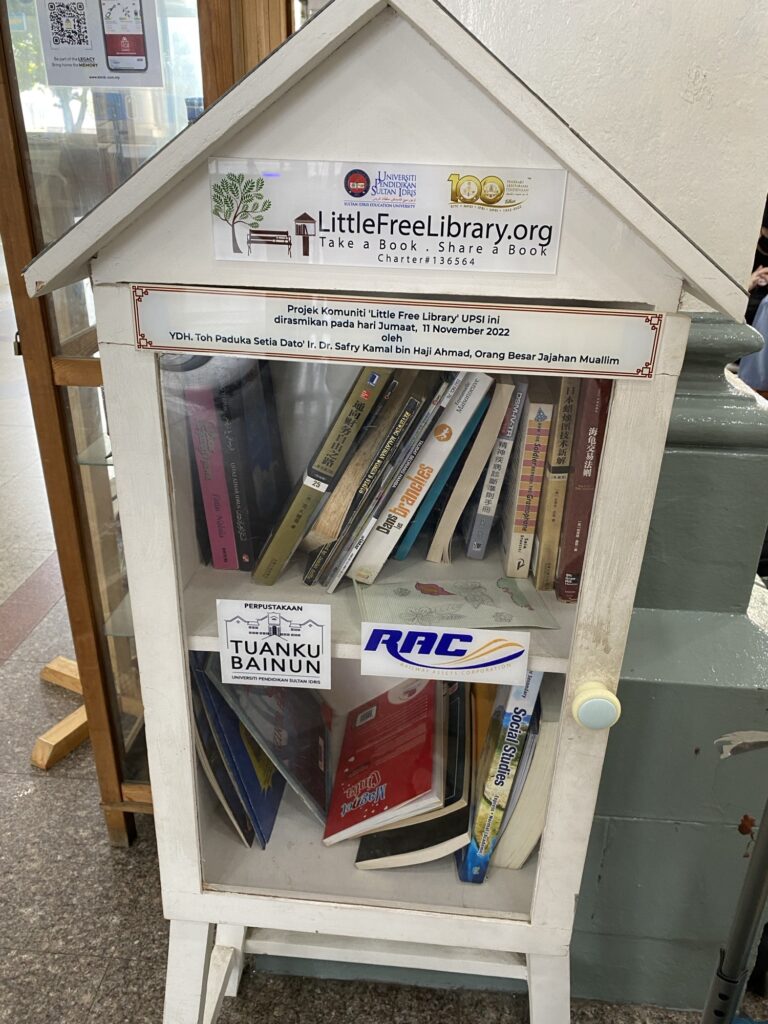 A small cabinet with a glass door. Inside are books in German, English, Chinese and Malay.