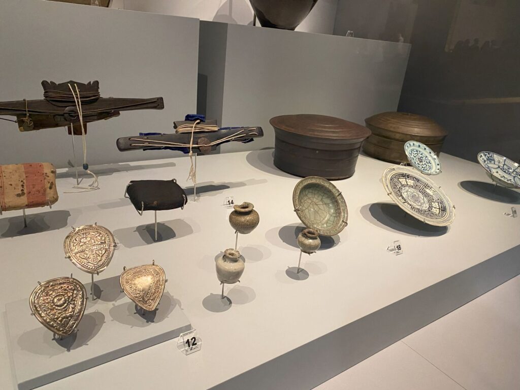 A selection of pottery items including highly decorated plates and tiny bottles.