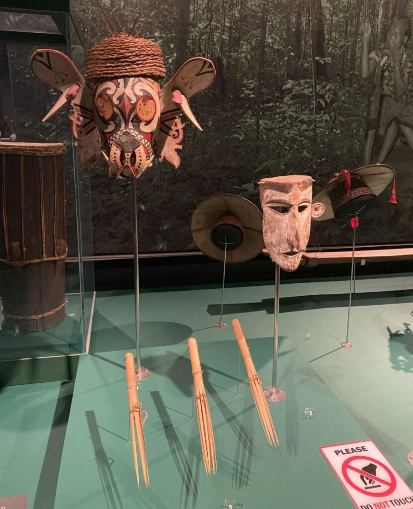 Two wooden carved masks, both painted in primary colors.