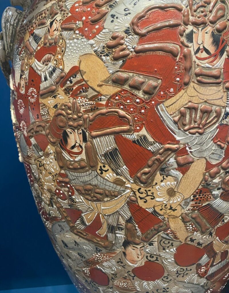 Close-up of a Chinese decorated vase showing a man with a mustache wearing armor.