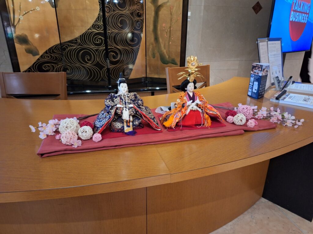 Two decorative dolls in traditional Japanese dress on the hotel front desk.