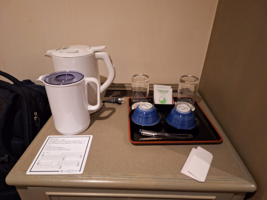 A hot water kettle, pitcher, green tea and traditional Japanese tea cups.